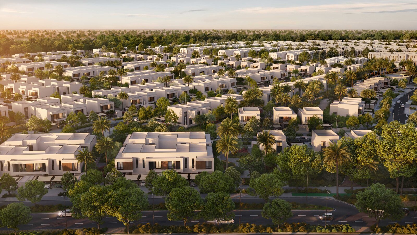 Aerial view over Al Ghadeer Parks by Aldar at golden hour, showing townhouses, villas and tree-lined streets